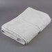 An Oxford Vicenza Bianco white bath towel folded on a gray surface.