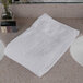 An Oxford Gold white cotton polyester blend bath towel with a dobby border on a counter top.