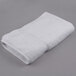 An Oxford Gold white 86/14 cotton polyester blend bath towel with a dobby border on a gray surface.