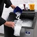 A person pouring ice into a Manitowoc undercounter ice machine.