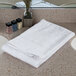 An Oxford Bronze white towel with a cam border on a counter.