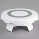 A white and green Wilton revolving cake stand with a green rim.