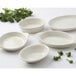 A group of Tuxton white oval dishes on a table with broccoli.