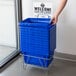 A person holding a Regency Blue plastic grocery market shopping basket.