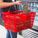 A woman holding a Regency red plastic shopping basket.