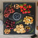 A Tablecraft faux slate melamine display tray with food on a table.