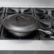 A Lodge cast iron skillet with a cover on a gas stove.
