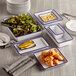 A group of rectangular blue speckled melamine serving bowls filled with food on a table.