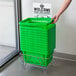 A person's hand holding a green Regency shopping basket.