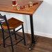 A Lancaster Table & Seating black bar height end column table base with glasses of beer on it.
