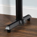 A Lancaster Table & Seating black metal bar height end table base with a flat metal leg.