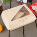 A Bagcraft Eco-Flute corrugated take-out box with a sandwich and a drink inside.