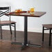 A Lancaster Table & Seating black cast iron table base with a glass of beer on it.