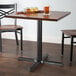 A Lancaster Table & Seating black cast iron table base with a glass of beer on it.