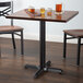 A Lancaster Table & Seating black cast iron table base with self-leveling feet supporting a table with glasses of beer on it.