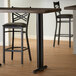 A Lancaster Table & Seating black cast iron end column table base on a bar table in a restaurant.
