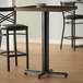A black Lancaster Table & Seating bar height table base with FLAT Tech levelers.