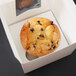 A chocolate chip muffin in a white box with a clear window and a Baker's Mark Reversible Cupcake / Muffin Insert.