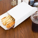 A Clay Coated Kraft food tray sleeve holding fried chicken and french fries on a table in a fast food restaurant.