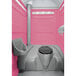 A PolyJohn pink portable restroom with a translucent top.
