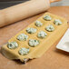 A metal tray with dough and green filling next to a Fox Run Jumbo Ravioli Maker and rolling pin.