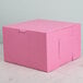 A pink bakery box with a lid on a marble surface.