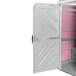A pink and white PolyJohn wheelchair accessible portable restroom with a door.