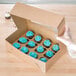 A Baker's Mark cupcake box with a dozen cupcakes with blue frosting and sprinkles.