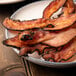 A plate of Kunzler Black Forest hardwood smoked bacon on a table.