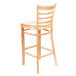 A Lancaster Table & Seating natural wood bar stool with a ladder back.