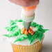 A person using an Ateco drop flower piping tip to decorate a cupcake.
