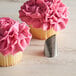 Two cupcakes with pink frosting piped using an Ateco Korean flower piping tip.