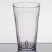 A Carlisle clear plastic tumbler with a clear rim on a table.