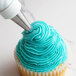 A person using an Ateco closed star piping tip to frost a cupcake with blue frosting.