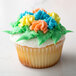 A cupcake with colorful frosting piped to look like flowers using an Ateco leaf piping tip.