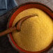 A bowl of Regal coarse yellow cornmeal with a wooden spoon.