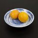 Two oranges on a blue and white bowl.