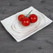 A rectangular taupe melamine plate with cherry tomatoes on a wood surface.
