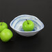 A blue oval melamine bowl filled with two green apples.