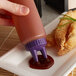 A hand using a Vollrath Twin Tip Squeeze Bottle to pour sauce on fried food.
