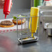 A Vollrath stainless steel holder with mustard and ketchup bottles on a counter.