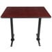 A Lancaster Table & Seating bar height rectangular table with a reversible cherry/black top and black cast iron table base plates.