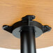 A black metal pole with a round wood surface on a Lancaster Table & Seating bar height table.