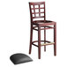 A Lancaster Table & Seating mahogany wood bar stool with a detached black vinyl seat.