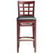A Lancaster Table & Seating mahogany wood bar stool with a black vinyl seat.