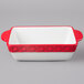 A white rectangular Tuxton casserole dish with a red border.