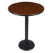 A round table with a Lancaster Table & Seating black cast iron base and reversible walnut and oak top.