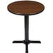 A Lancaster Table & Seating round table with a reversible wooden top and black base.