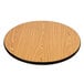 A Lancaster Table & Seating round wooden table with a reversible walnut and oak table top on a cross cast iron base.