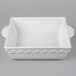 A Tuxton bright white square ceramic casserole dish with handles.